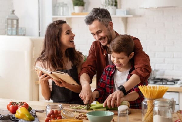 Homepage - Happy Family Laughing Loud and Cooking on the Kitchen Counter as They Prepare for Dinner Together